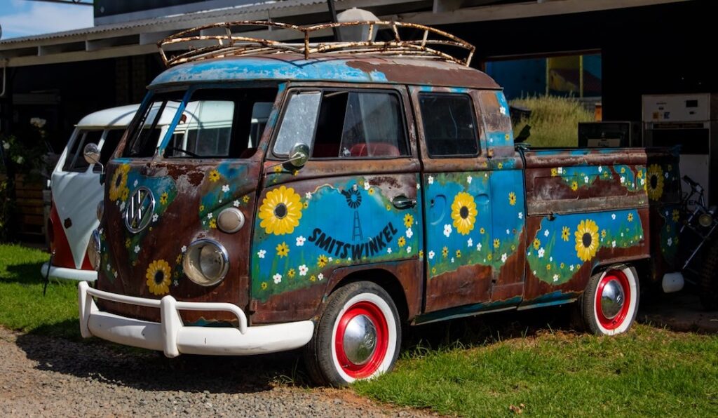 Volkswagen Transporter T1 hippie, cu flori și simboluri peace, expus în aer liber