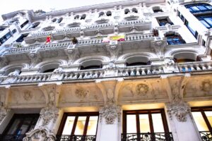 Fațadă istorică pe Calle Mayor din Madrid, cu detalii arhitecturale elegante și steaguri ale Spaniei